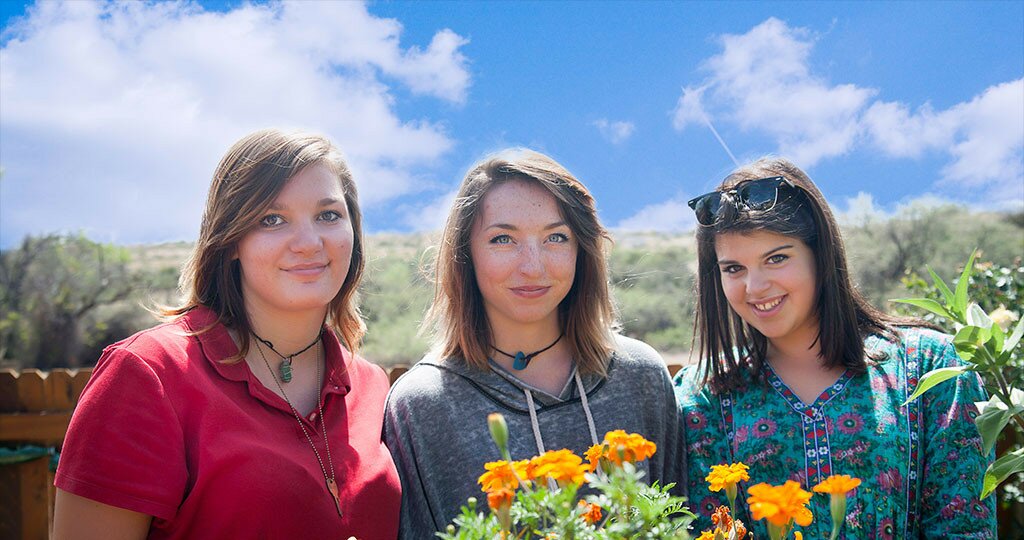 smiling girls with blue sky and flowers around them